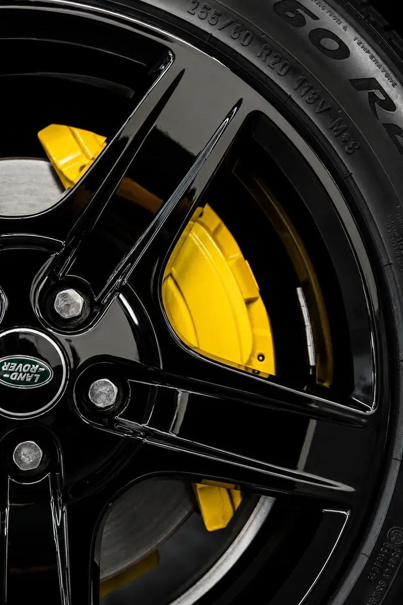 Close-up of gloss black powder-coated Land Rover wheel with custom yellow brake caliper — Hussle Customz Los Angeles